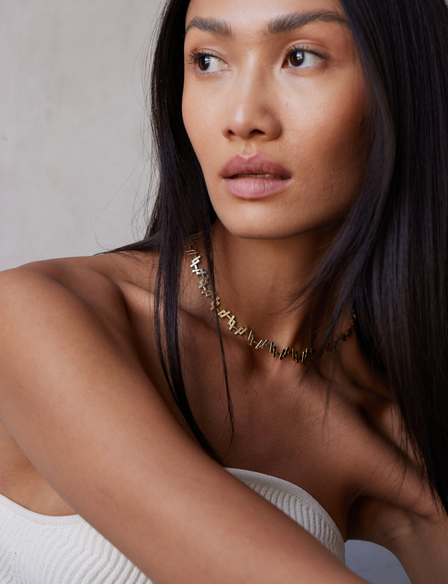 a female model wearing an 18k Gold chain link necklace on a white background