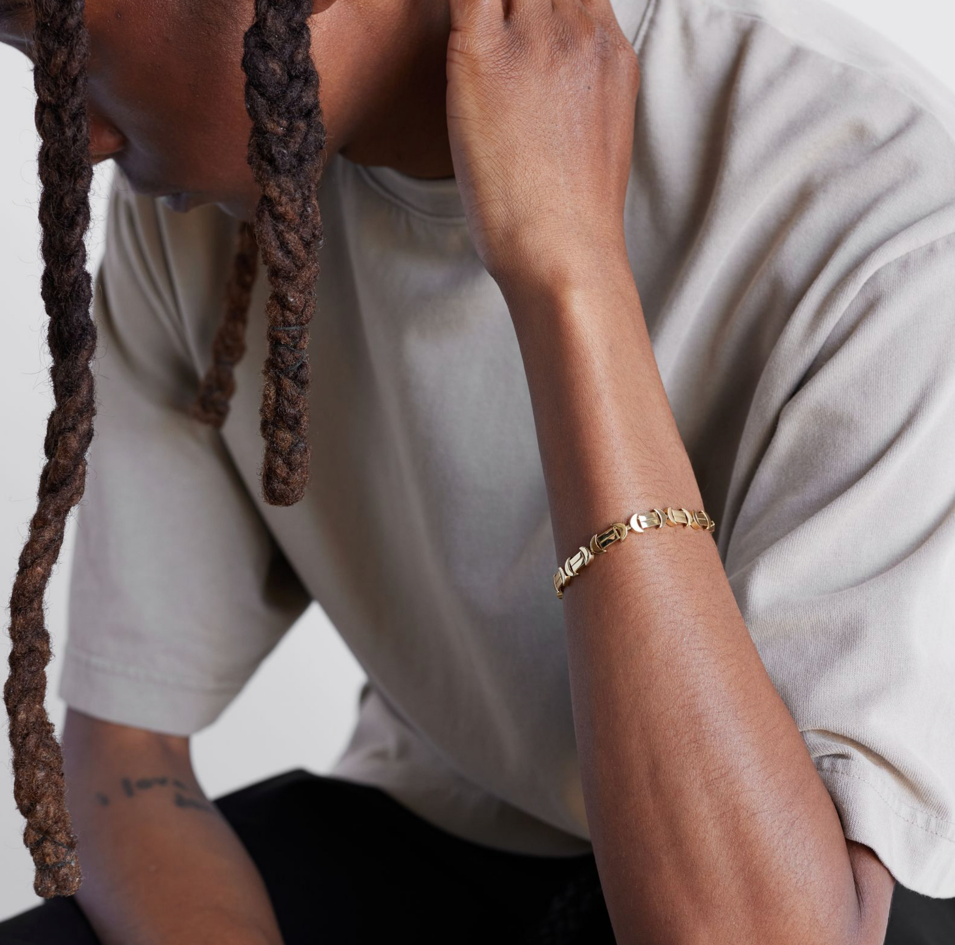 A model shot of a gold bracelet with a chain of linked half-moon crescent shapes, crafted in an Art Deco style.