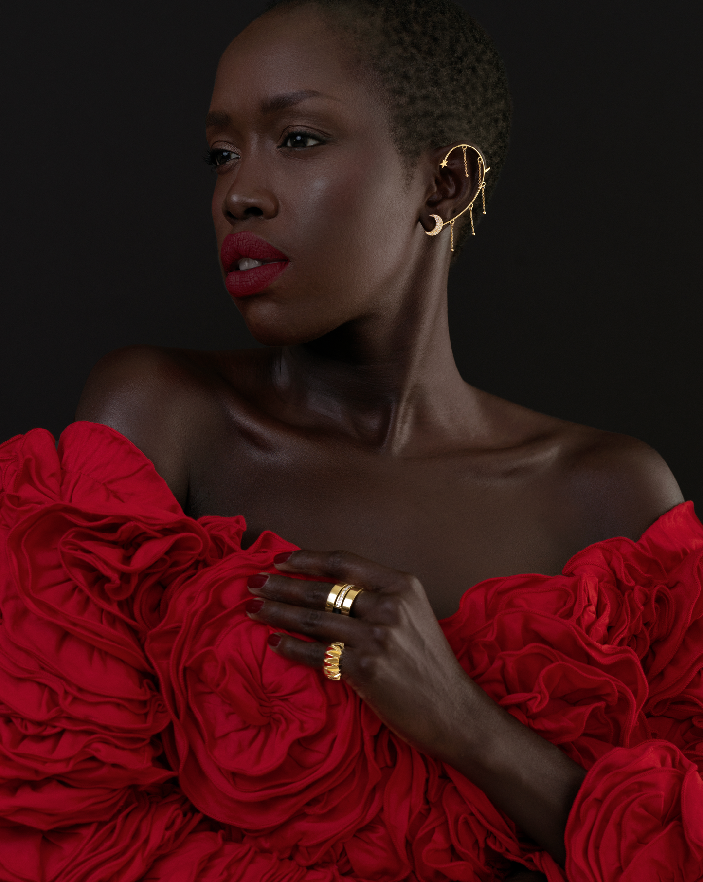 a female model wearing a gold textured pinky ring and a red dress