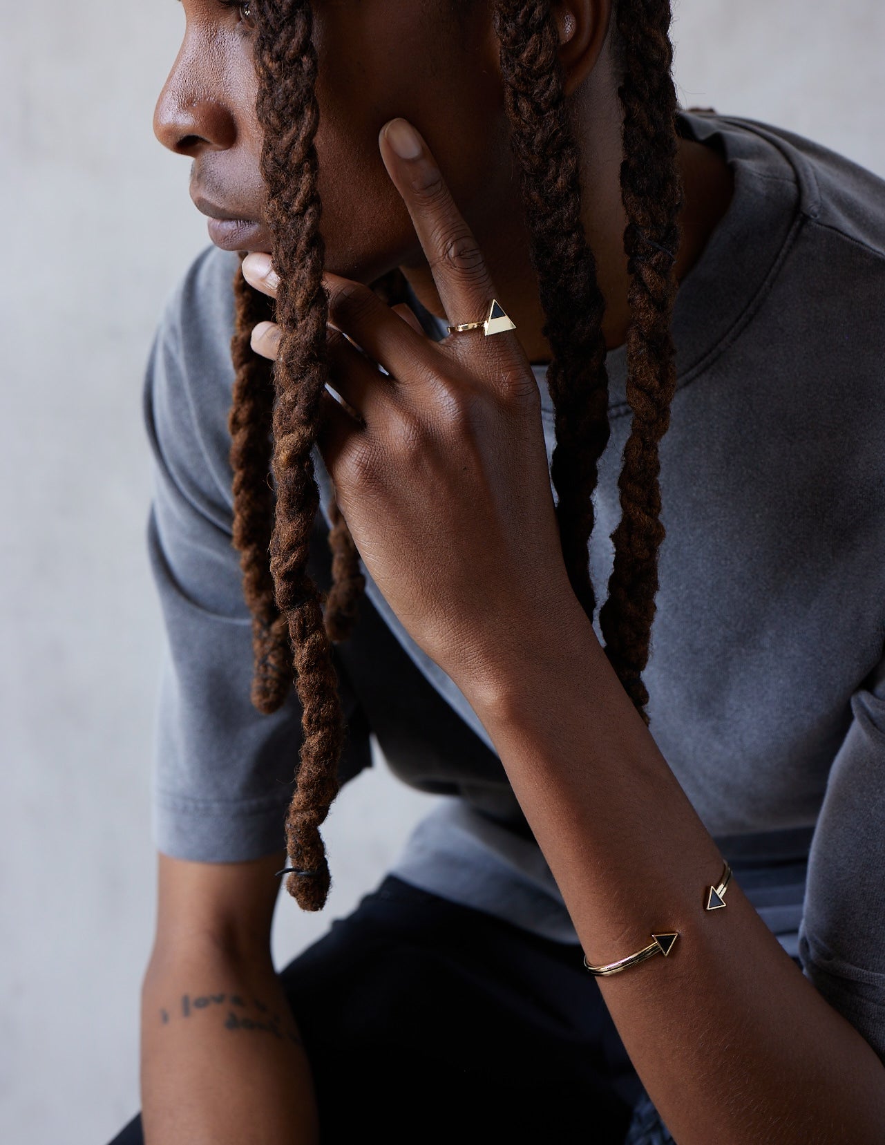 Model wearing a gold open bangle with black enamel piping