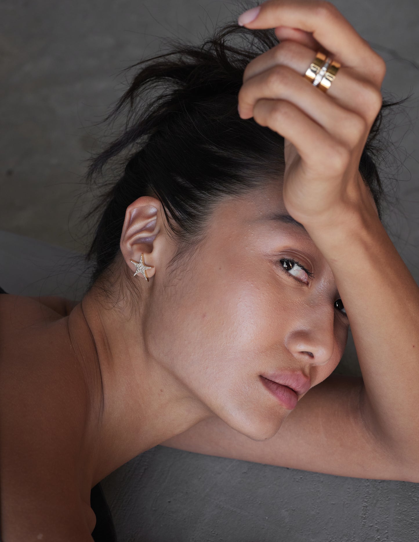 female model wearing 18k yellow gold star-shaped earrings with embedded diamonds creating a 'star-burst' effect.