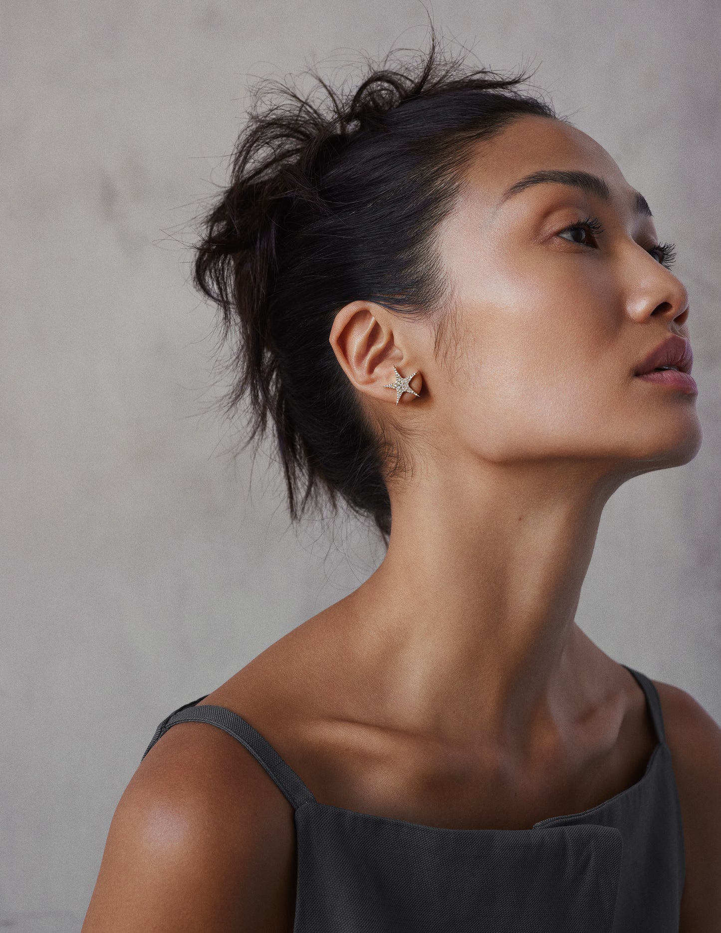 female model wearing 18k yellow gold star-shaped earrings with embedded diamonds creating a 'star-burst' effect.