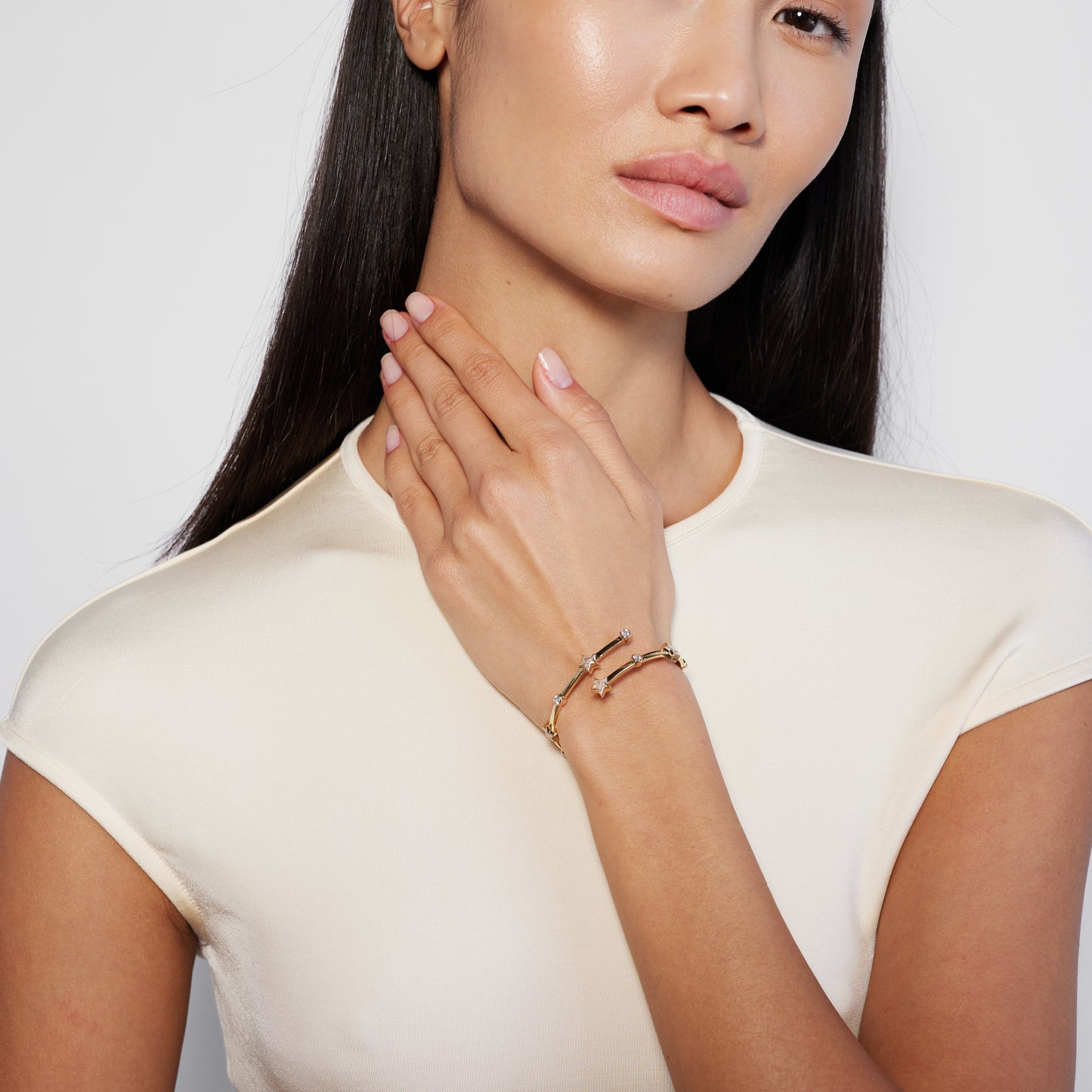 Model shot of a wrap-around bangle bracelet with a gold color and adorned with star-shaped sapphires