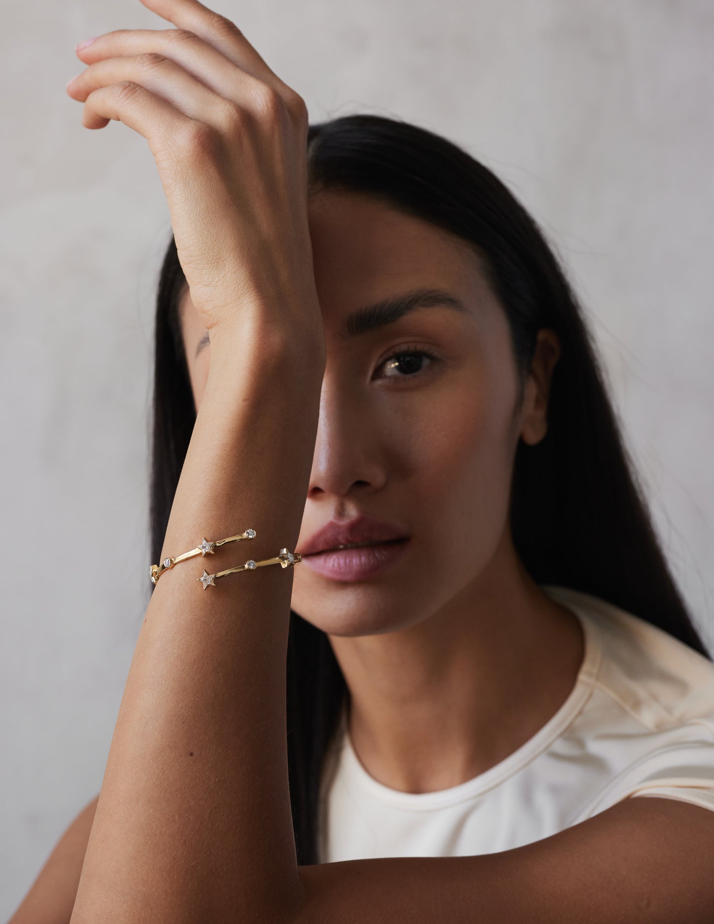 A model shot of a wrap-around bangle bracelet with a gold color and adorned with star-shaped sapphires
