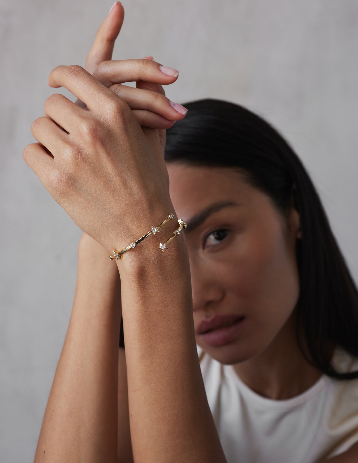 A model shot of a wrap-around bangle bracelet with a gold color and adorned with star-shaped sapphires