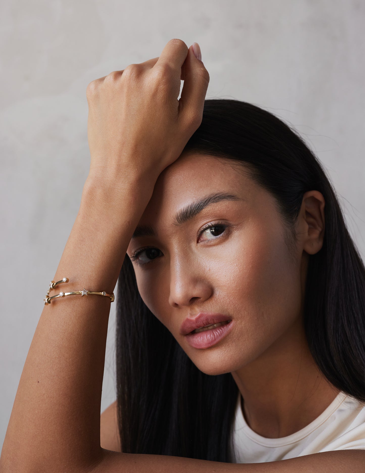 A model shot of a wrap-around bangle bracelet with a gold color and adorned with star-shaped sapphires