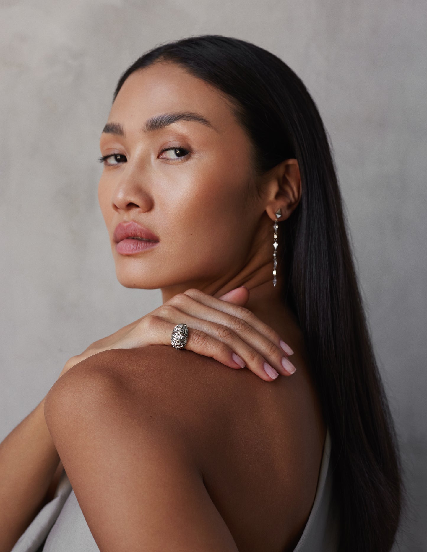 female model wearing a vintage-style dome-shaped ring with a central diamond surrounded by smaller diamonds set in 18k white gold.