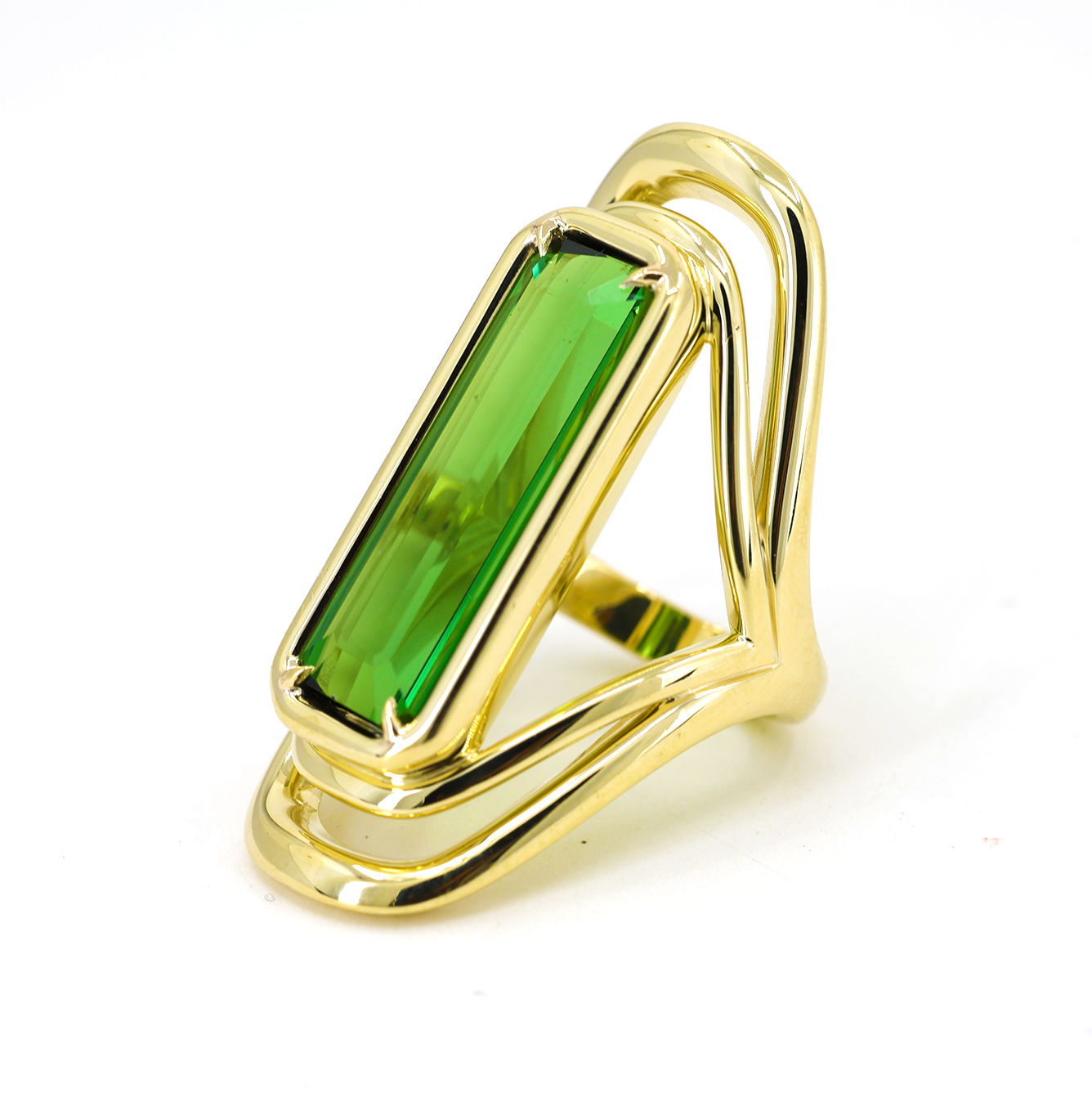 A LÖF gold ring featuring a large green tourmaline stone with a unique swooping band design.
