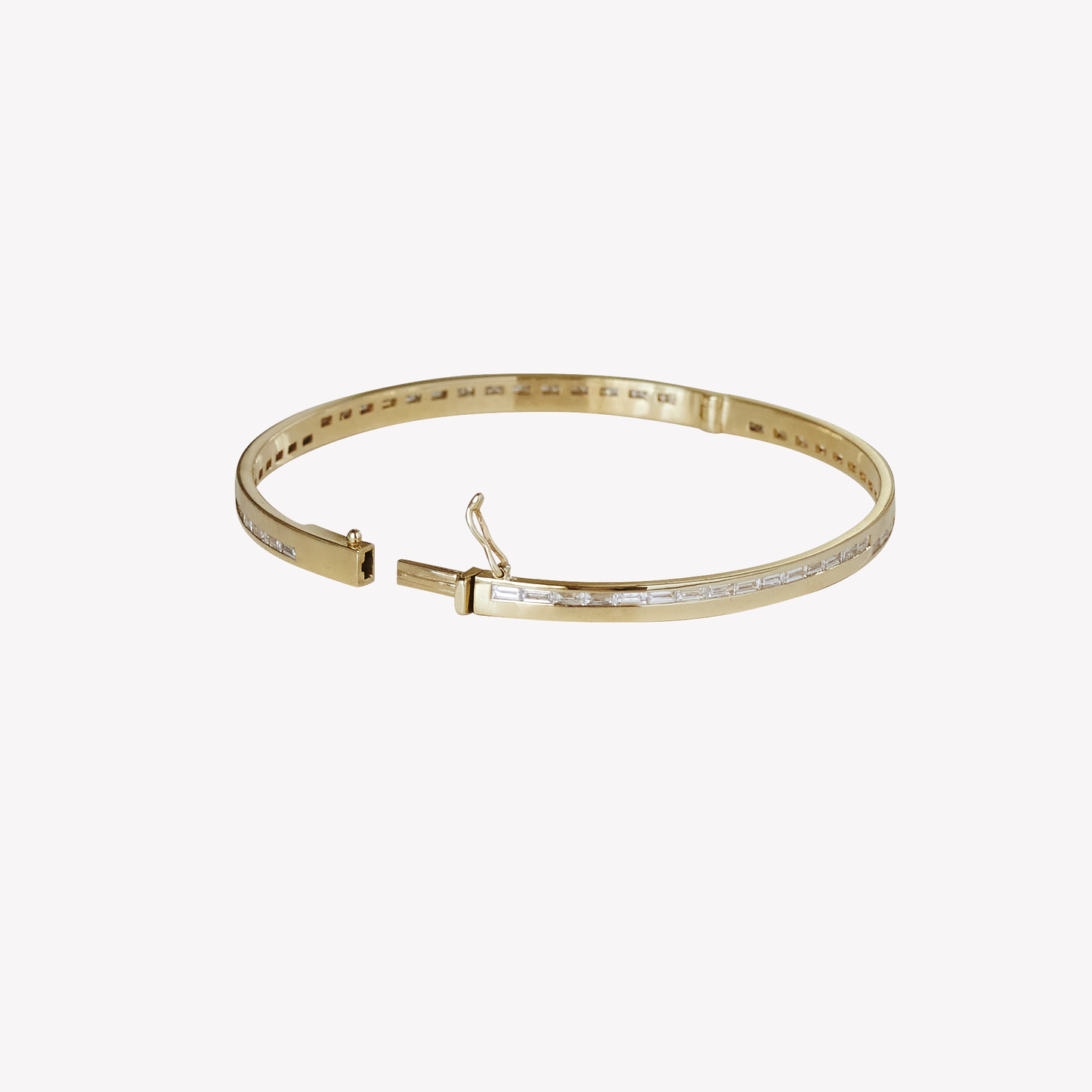 a yellow gold and baguette diamond bangle showing the push clasp