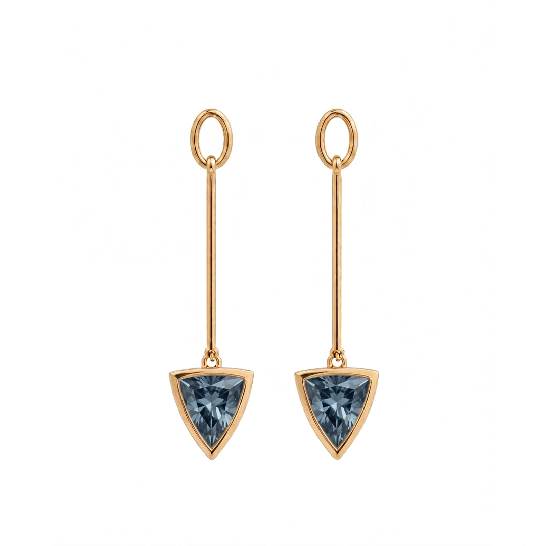 A pair of gold drop earrings featuring a triangular faceted blue spinel gemstone in a gold bezel setting, suspended from a thin vertical bar with a circular top loop, shown on a plain white background.