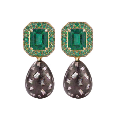A pair of drop earrings featuring rectangular emerald-cut emeralds surrounded by small green stones in gold-toned settings, with teardrop-shaped dark gray pavé drops set with clear baguette and round stones, shown on a white background.