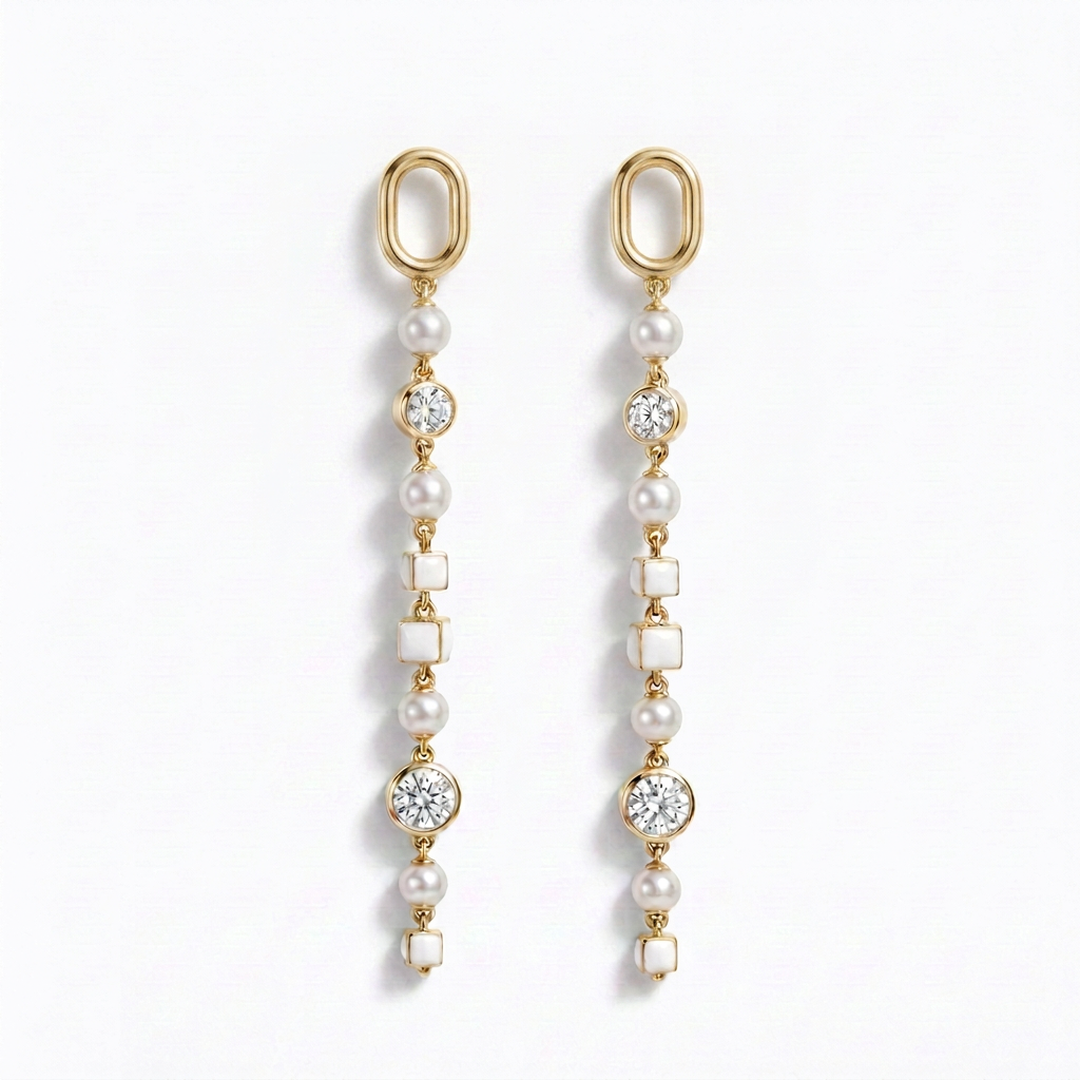 A pair of gold dangle earrings with white pearls, clear round diamonds, and white square shell-like beads, displayed on a clean white background.