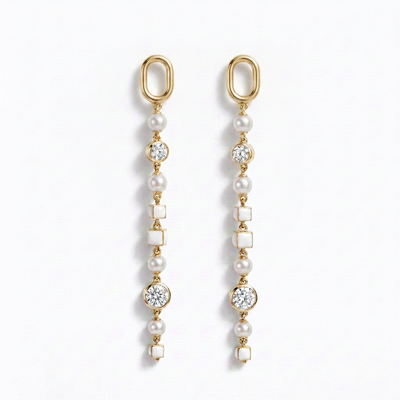 A pair of gold dangle earrings with white pearls, clear round diamonds, and white square shell-like beads, displayed on a clean white background.