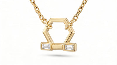 A gold geometric pendant necklace featuring a hexagonal design with two rectangular bezel-set clear baguette diamonds, suspended from a delicate gold chain against a white background.