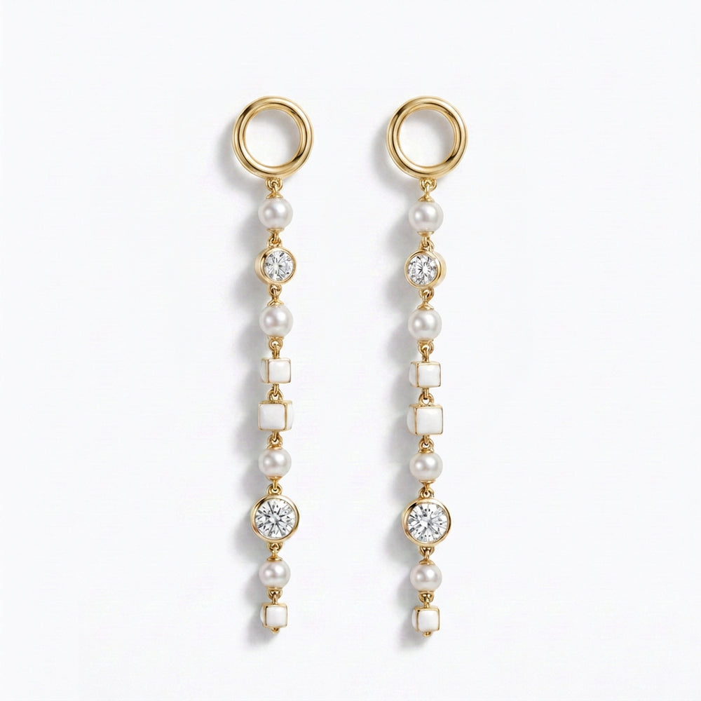 A pair of gold dangle earrings with whitenatural pearls, white square inlays, and old european cut diamond accents, shown on a clean white background.