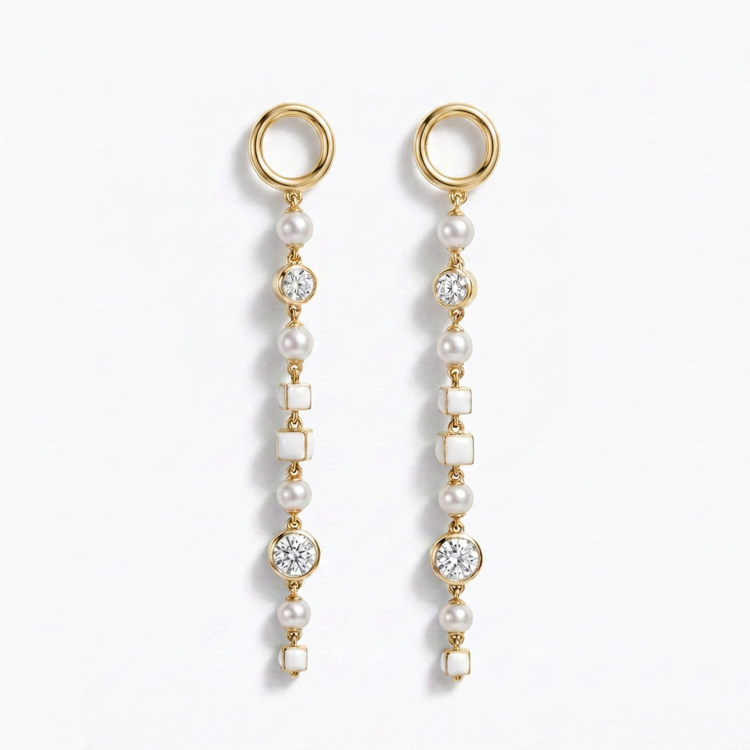A pair of gold dangle earrings with whitenatural pearls, white square inlays, and old european cut diamond accents, shown on a clean white background.