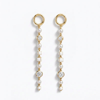 A pair of gold dangle earrings with whitenatural pearls, white square inlays, and old european cut diamond accents, shown on a clean white background.