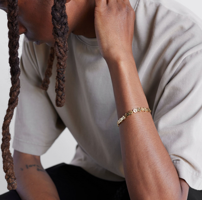 A model shot of a gold bracelet with a chain of linked half-moon crescent shapes, crafted in an Art Deco style.