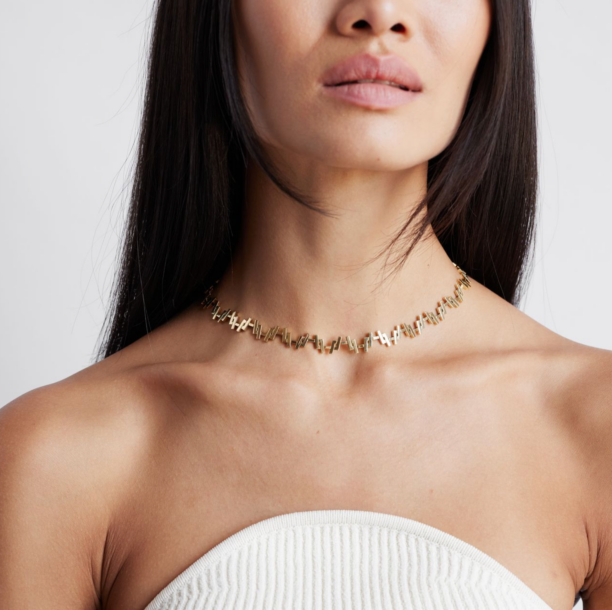 a female model wearing an 18k Gold chain link necklace on a white background