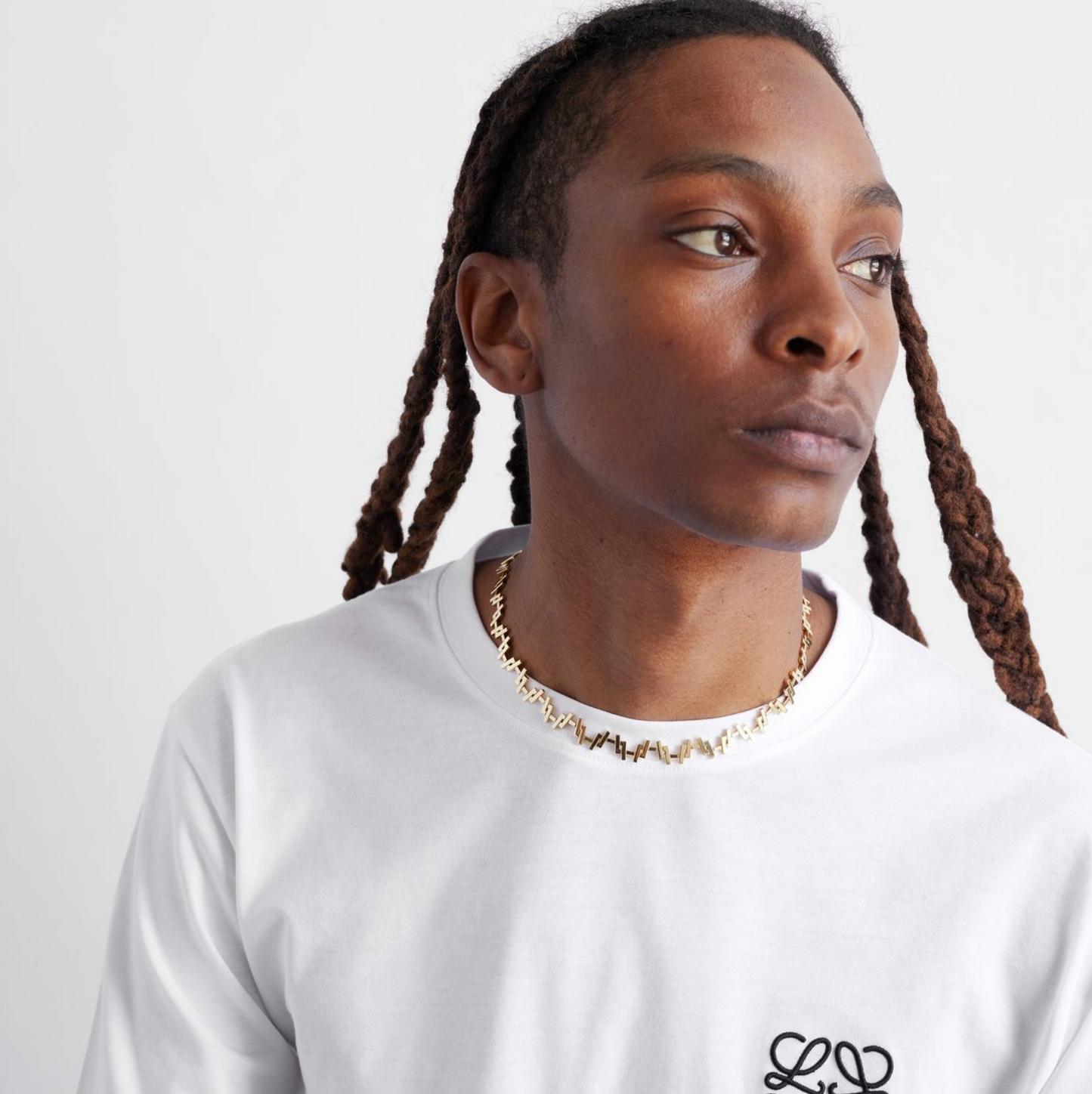 a male model wearing an 18k Gold chain link necklace on a white background