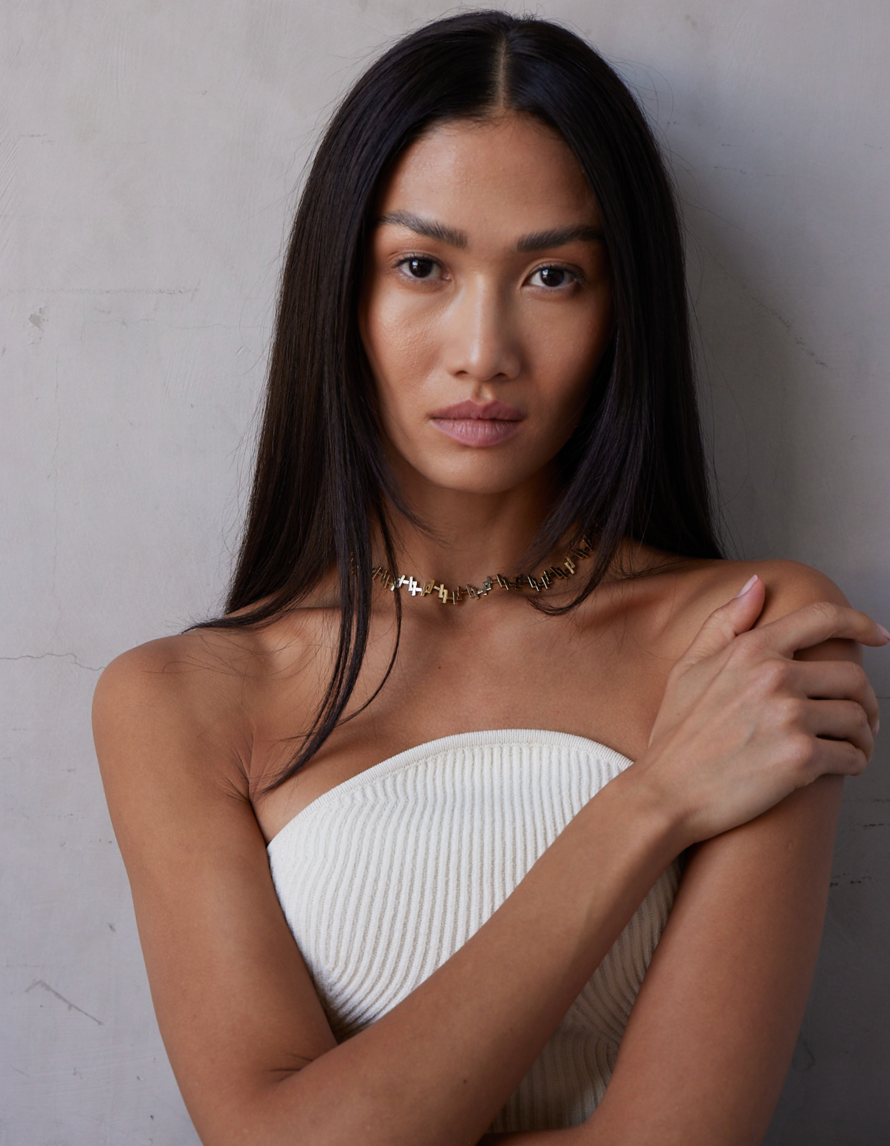a female model wearing an 18k Gold chain link necklace on a white background