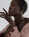 A model shot gold ring with a geometric design featuring two vertical polished gold bars and one horizontal bar set with baguette cut emeralds