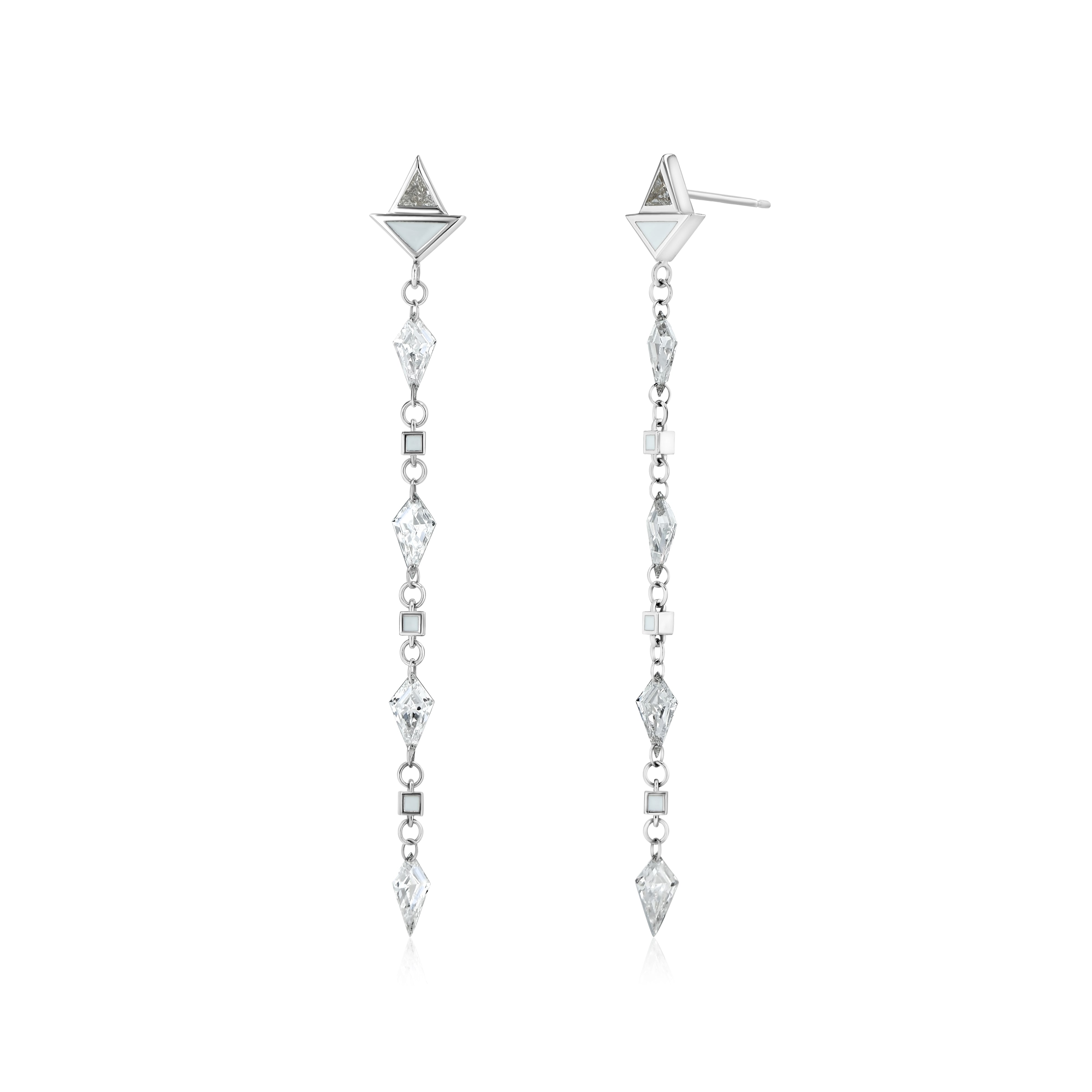 A pair of white gold earrings featuring kite-shaped white diamonds and white enamel details.