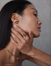 A model wearing pair of gold stud earrings with pinstripe bar design set with either diamonds or emeralds.