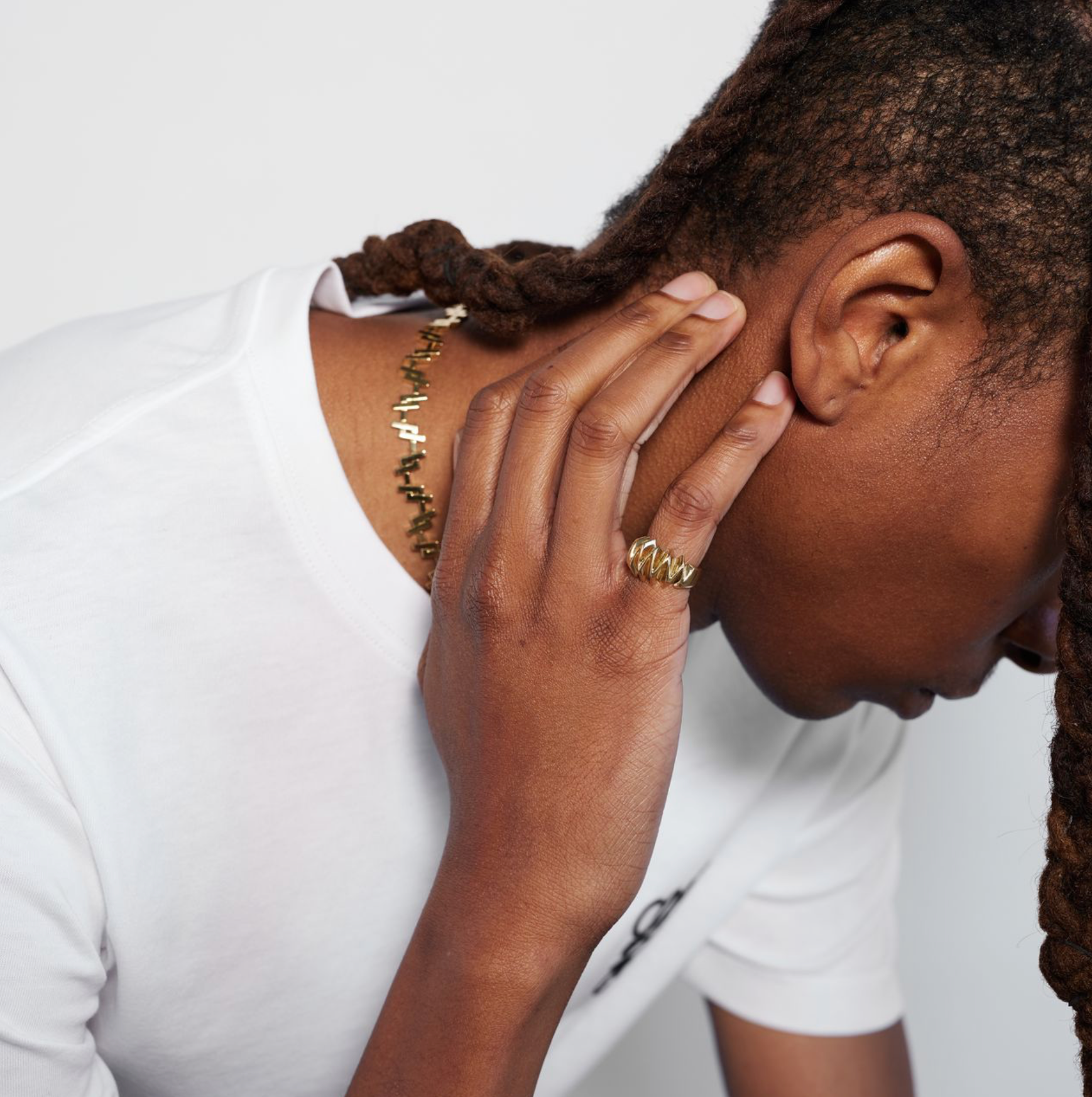 A person wearing a white t-shirt with the Édith Ring on their pinky finger.